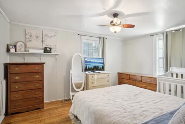 bedroom with light hardwood / wood-style floors, ceiling fan, and ornamental molding