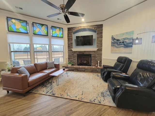 living room with a fireplace, hardwood / wood-style floors, ceiling fan, and crown molding