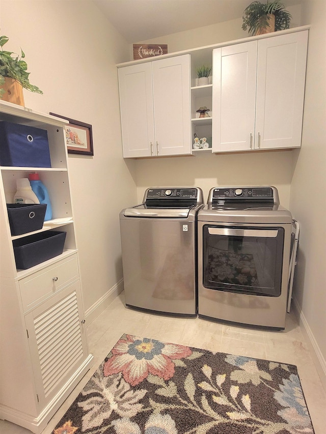 laundry room featuring washing machine and clothes dryer, light tile patterned floors, and cabinets