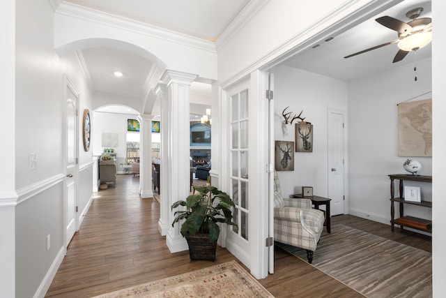 corridor featuring dark hardwood / wood-style floors, ornate columns, and ornamental molding