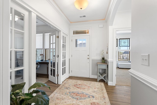 foyer with a healthy amount of sunlight, dark hardwood / wood-style flooring, crown molding, and french doors