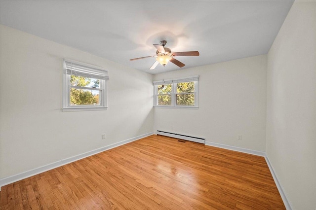 spare room with ceiling fan, baseboard heating, and light hardwood / wood-style flooring