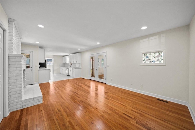 unfurnished living room with light hardwood / wood-style flooring and a brick fireplace