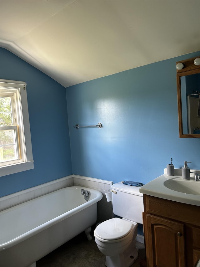 bathroom with a bathing tub, vanity, vaulted ceiling, and toilet