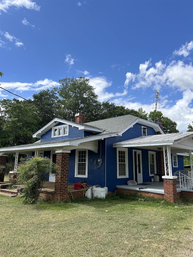 rear view of property featuring a lawn and a porch