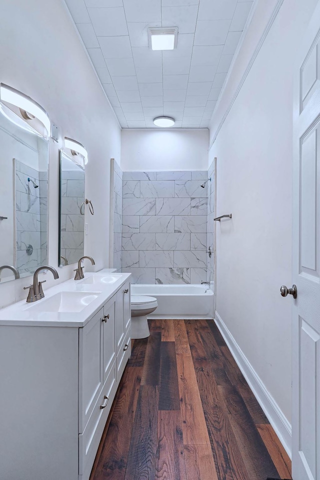 full bathroom featuring hardwood / wood-style floors, vanity, tiled shower / bath, toilet, and ornamental molding