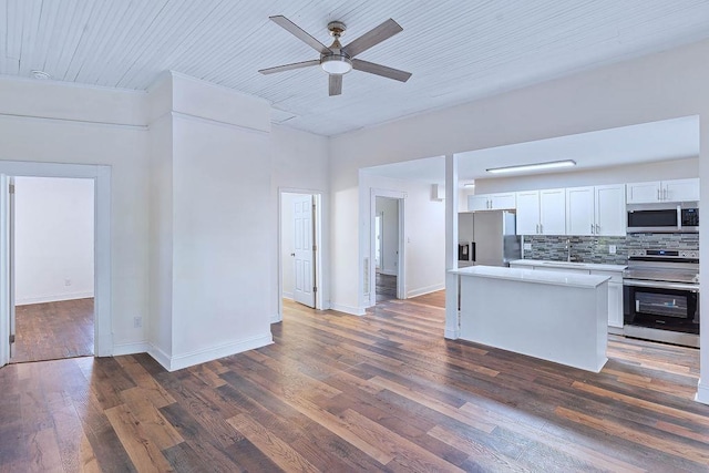 kitchen featuring decorative backsplash, appliances with stainless steel finishes, dark hardwood / wood-style flooring, and white cabinetry