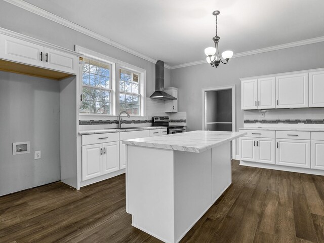 kitchen with stainless steel range with electric stovetop, white cabinets, wall chimney range hood, sink, and hanging light fixtures