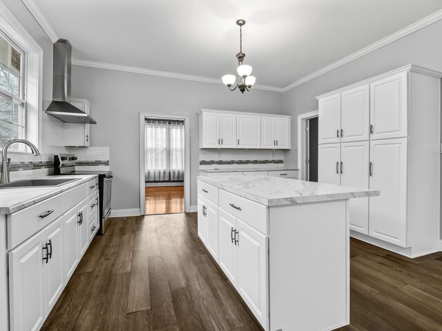 kitchen featuring a center island, sink, hanging light fixtures, wall chimney exhaust hood, and white cabinetry