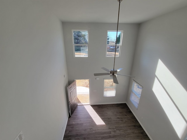 unfurnished living room featuring a high ceiling, dark hardwood / wood-style floors, and ceiling fan