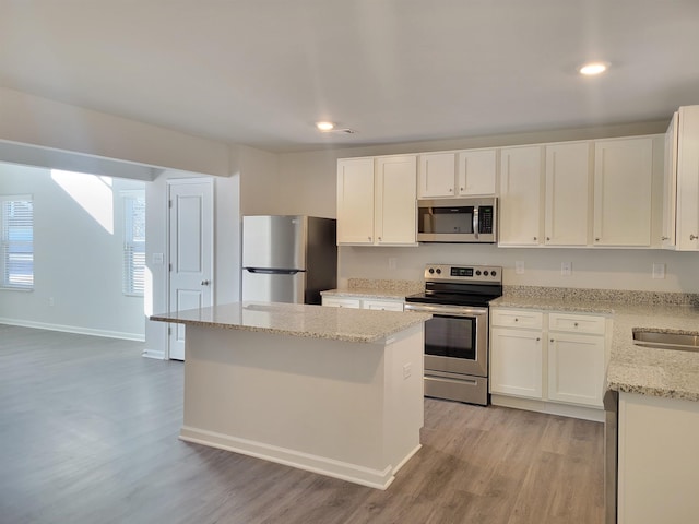 kitchen with white cabinetry, a center island, light wood-type flooring, and appliances with stainless steel finishes