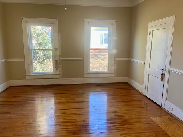 unfurnished room with light wood-type flooring, a wealth of natural light, and ornamental molding