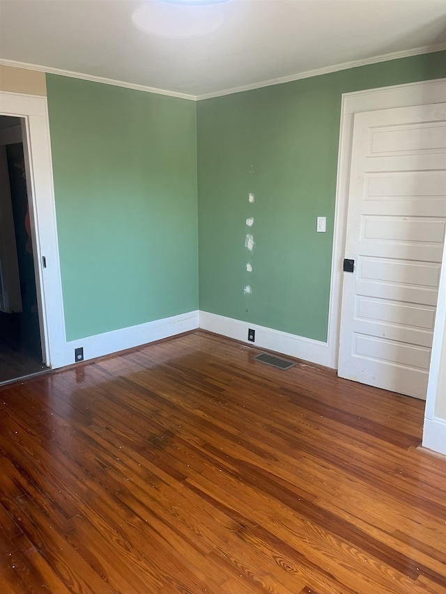 empty room with wood-type flooring and crown molding