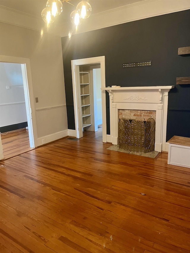 unfurnished living room with wood-type flooring, built in features, and crown molding