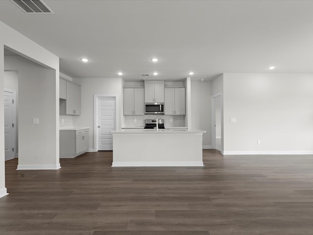 kitchen with tasteful backsplash, stainless steel appliances, dark hardwood / wood-style flooring, and an island with sink