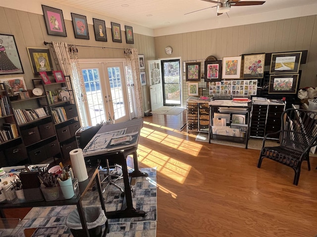 office area with wooden walls, hardwood / wood-style floors, ceiling fan, and french doors