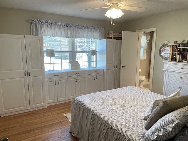 bedroom featuring ensuite bath, ceiling fan, light hardwood / wood-style floors, and a textured ceiling