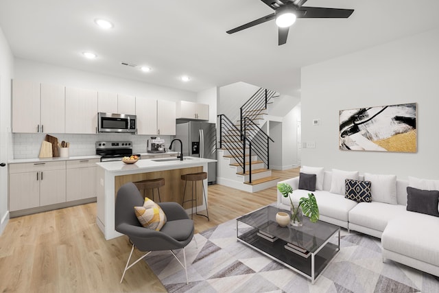 living room with ceiling fan, light hardwood / wood-style flooring, and sink