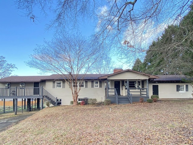 ranch-style home with covered porch, central air condition unit, and a front lawn