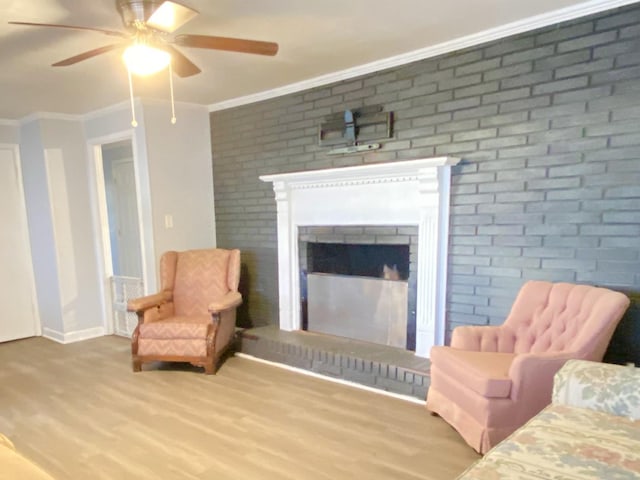 living area featuring light hardwood / wood-style floors, a brick fireplace, ceiling fan, and ornamental molding