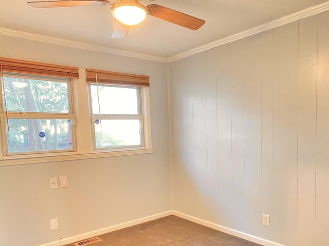 carpeted empty room with ceiling fan, a healthy amount of sunlight, and crown molding