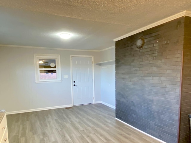 spare room featuring ornamental molding, a textured ceiling, and light hardwood / wood-style flooring