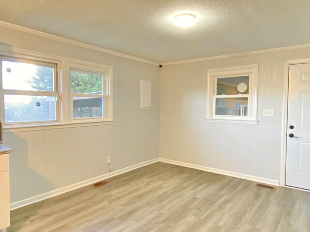 unfurnished room featuring light hardwood / wood-style floors, a textured ceiling, and ornamental molding