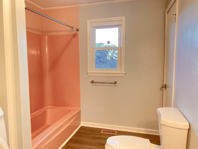 bathroom featuring bathing tub / shower combination, toilet, ornamental molding, and hardwood / wood-style flooring