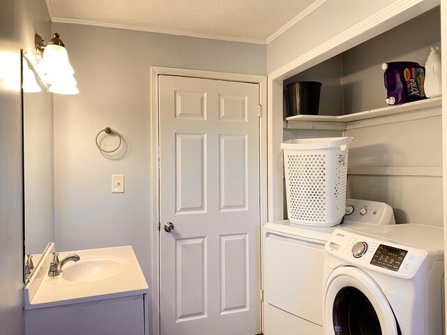 laundry area with washer and dryer, a textured ceiling, ornamental molding, and sink