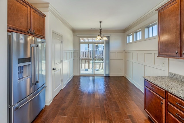 kitchen with high end refrigerator, decorative light fixtures, ornamental molding, a notable chandelier, and light stone counters