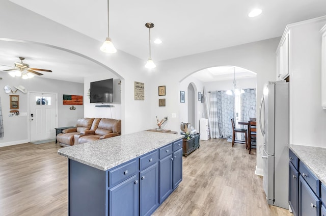 kitchen with ceiling fan with notable chandelier, blue cabinetry, decorative light fixtures, white cabinetry, and stainless steel refrigerator