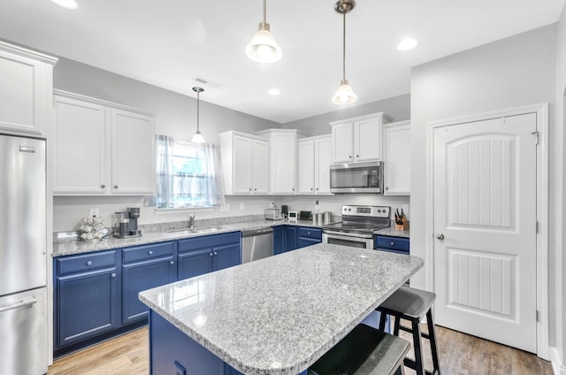 kitchen featuring pendant lighting, white cabinets, blue cabinets, a kitchen island, and stainless steel appliances