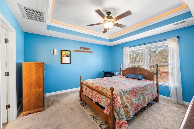 carpeted bedroom with a tray ceiling, ceiling fan, and ornamental molding