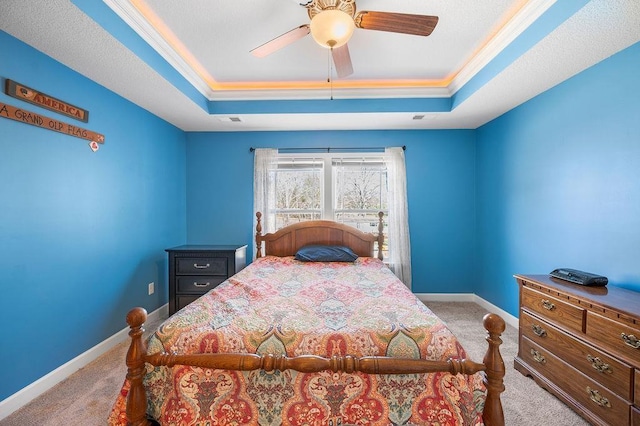 carpeted bedroom featuring ceiling fan, a raised ceiling, and ornamental molding