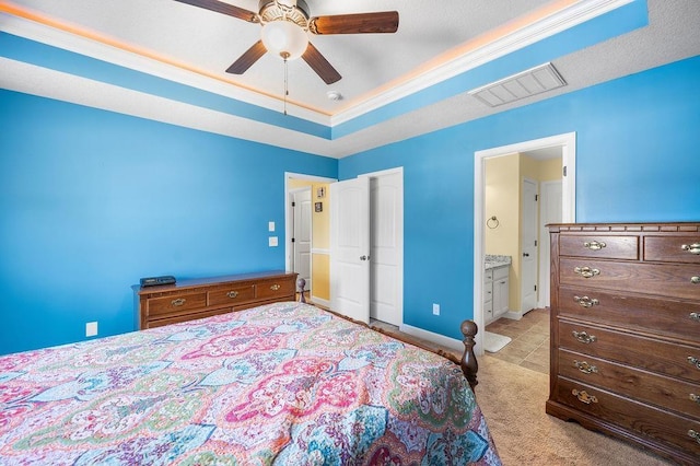 bedroom with a tray ceiling, ceiling fan, and ensuite bathroom