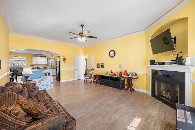 living room with ceiling fan, crown molding, and light hardwood / wood-style flooring