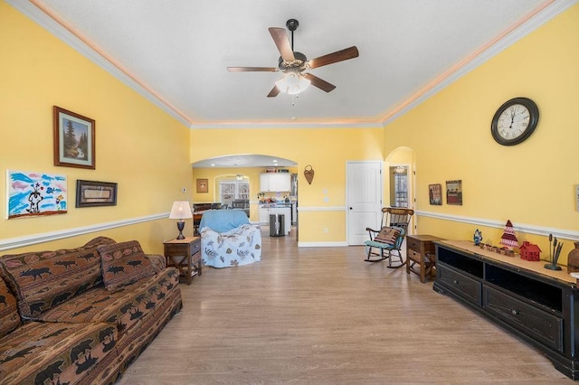 living room with crown molding, ceiling fan, and light wood-type flooring