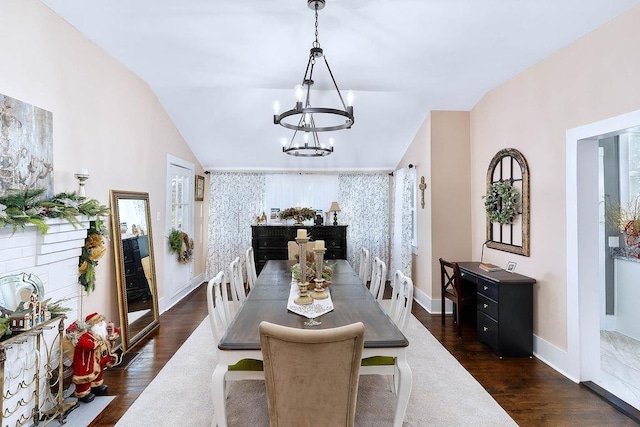 dining area with an inviting chandelier, vaulted ceiling, and dark wood-type flooring