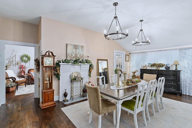 dining space with dark hardwood / wood-style floors, lofted ceiling, and an inviting chandelier