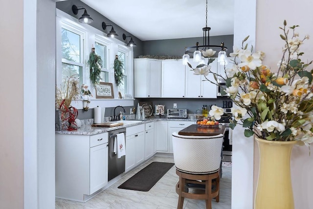 kitchen featuring stainless steel dishwasher, sink, dark stone countertops, white cabinets, and hanging light fixtures