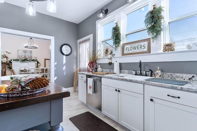 kitchen featuring dishwasher, sink, a chandelier, decorative light fixtures, and white cabinets