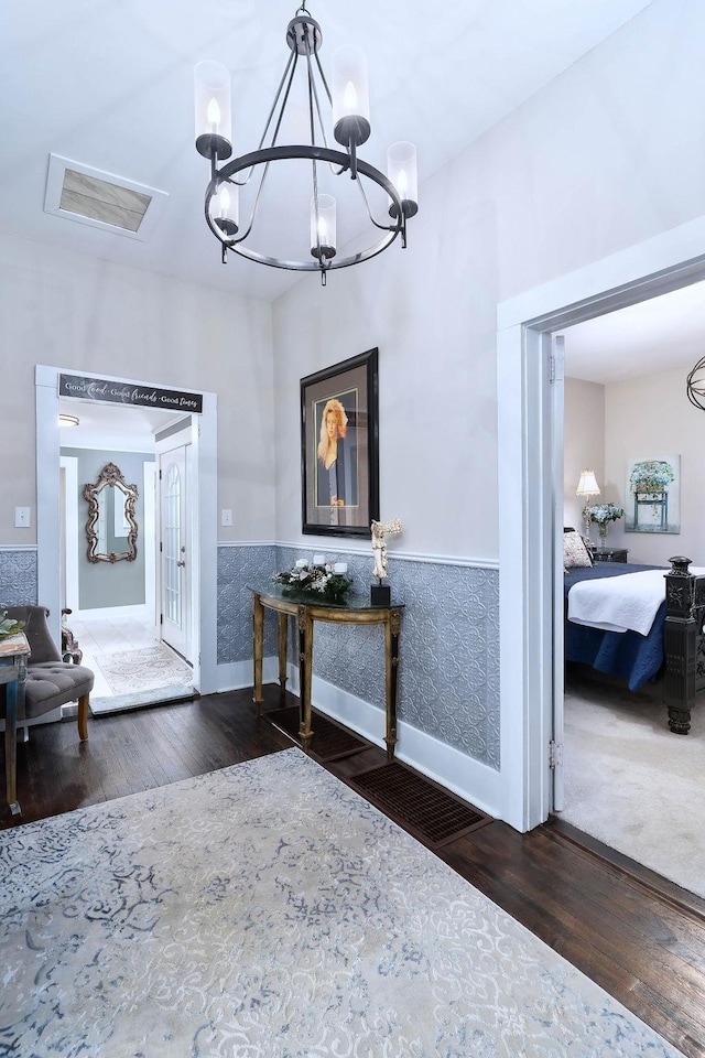 foyer with dark wood-type flooring, tile walls, and an inviting chandelier