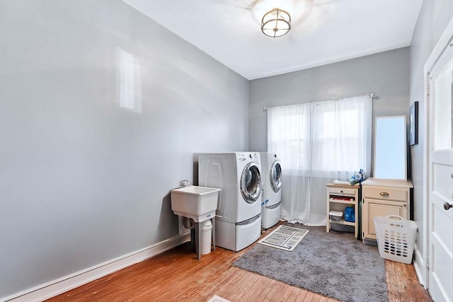 laundry room featuring sink, light hardwood / wood-style flooring, and washing machine and clothes dryer