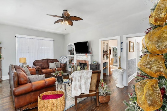 living room featuring a fireplace, ceiling fan, built in features, and dark wood-type flooring