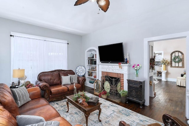 living room with a fireplace, dark hardwood / wood-style flooring, built in features, and ceiling fan