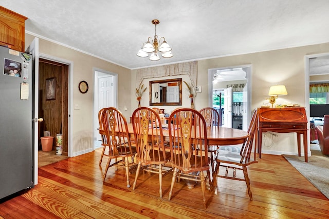 dining room with light hardwood / wood-style floors, an inviting chandelier, a wealth of natural light, and crown molding