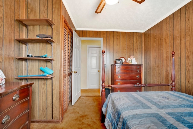 carpeted bedroom featuring ceiling fan, wood walls, crown molding, and a closet