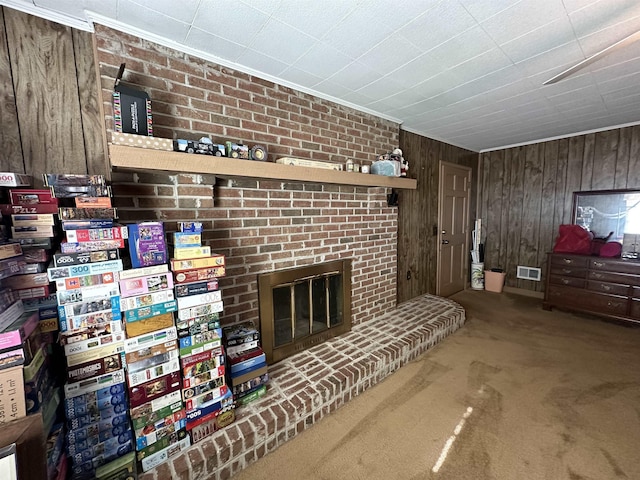 carpeted living room with a fireplace, crown molding, and wooden walls