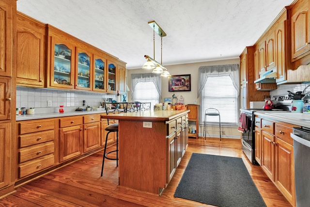 kitchen with pendant lighting, a breakfast bar, tasteful backsplash, a kitchen island, and stainless steel appliances