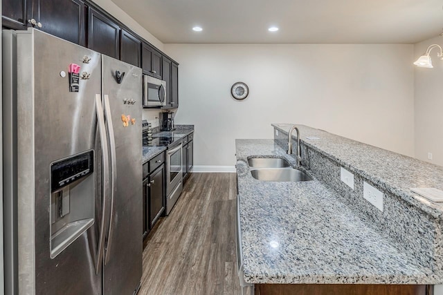 kitchen featuring light stone counters, sink, stainless steel appliances, and dark hardwood / wood-style floors